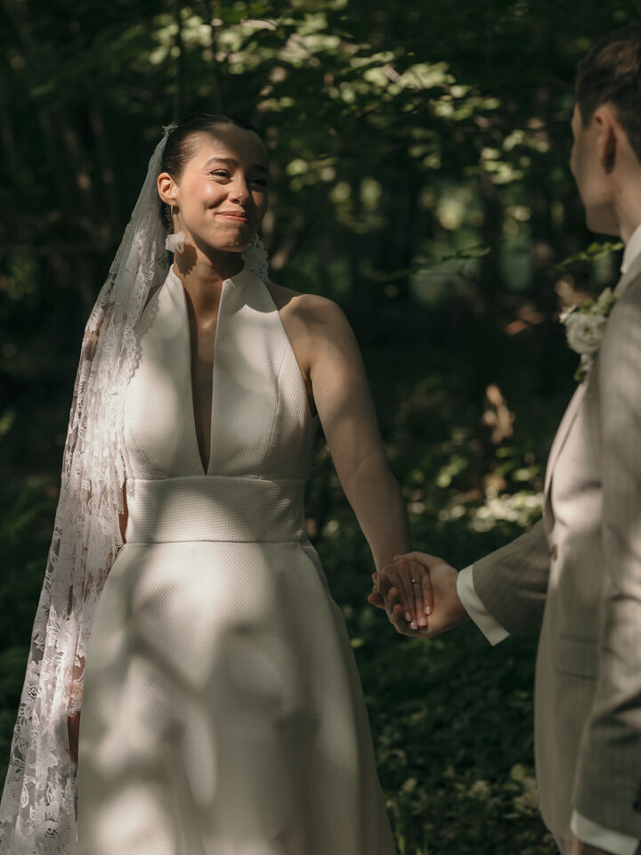 De bruid wandelt in het bos in Oldenzaal gelegen in Twente, haar hand vastghouden door haar aanstaande man.