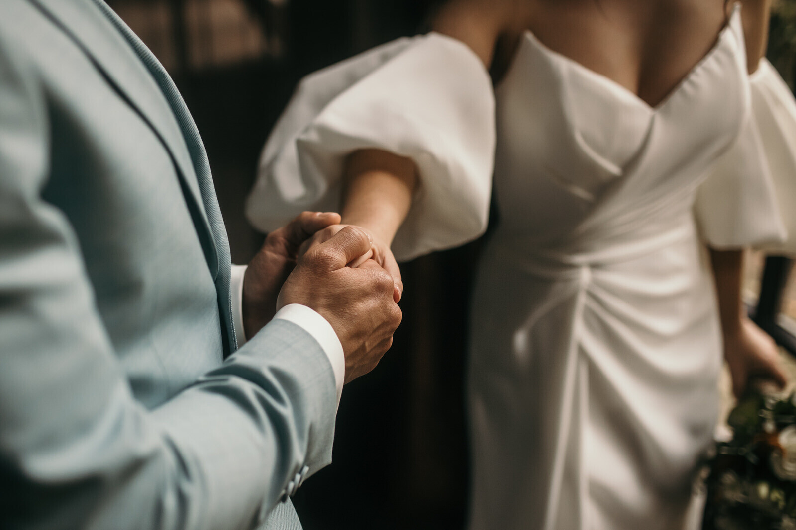 Liefdevol pakt de bruidegom de hand van de bruid vast met twee handen.