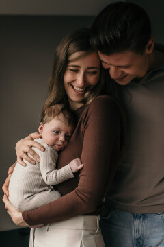 Een baby wordt vastgehouden in de armen van de moeder.