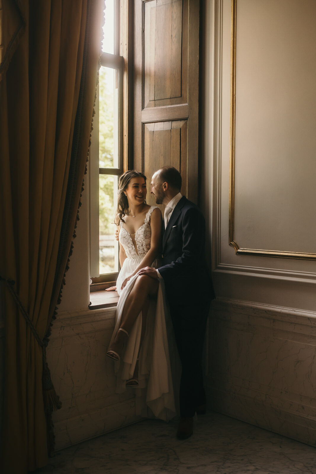 Trouwfotograaf Foto Danielle uit Denekamp heeft het bruidspaar vastgelegd bij het raam van museum More Twickel.